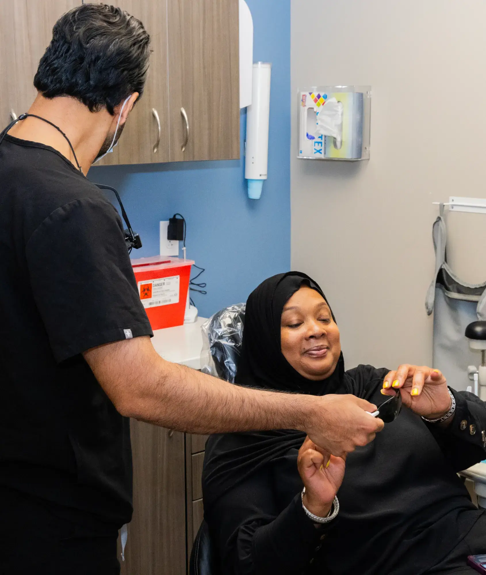 A dental professional helps a woman in a chair at a dental clinic.