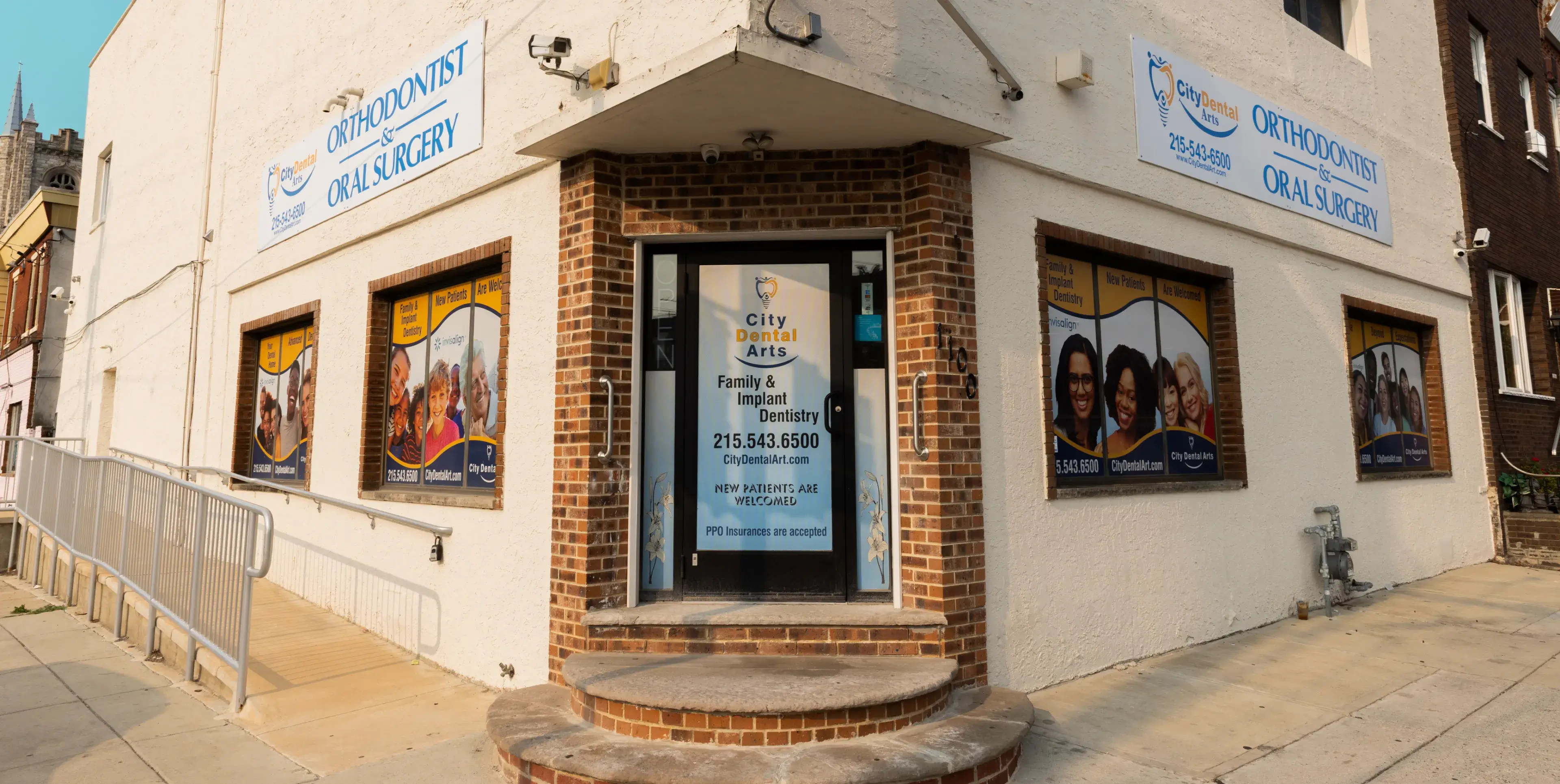 A corner dental clinic with large windows and signs for orthodontics and oral surgery.