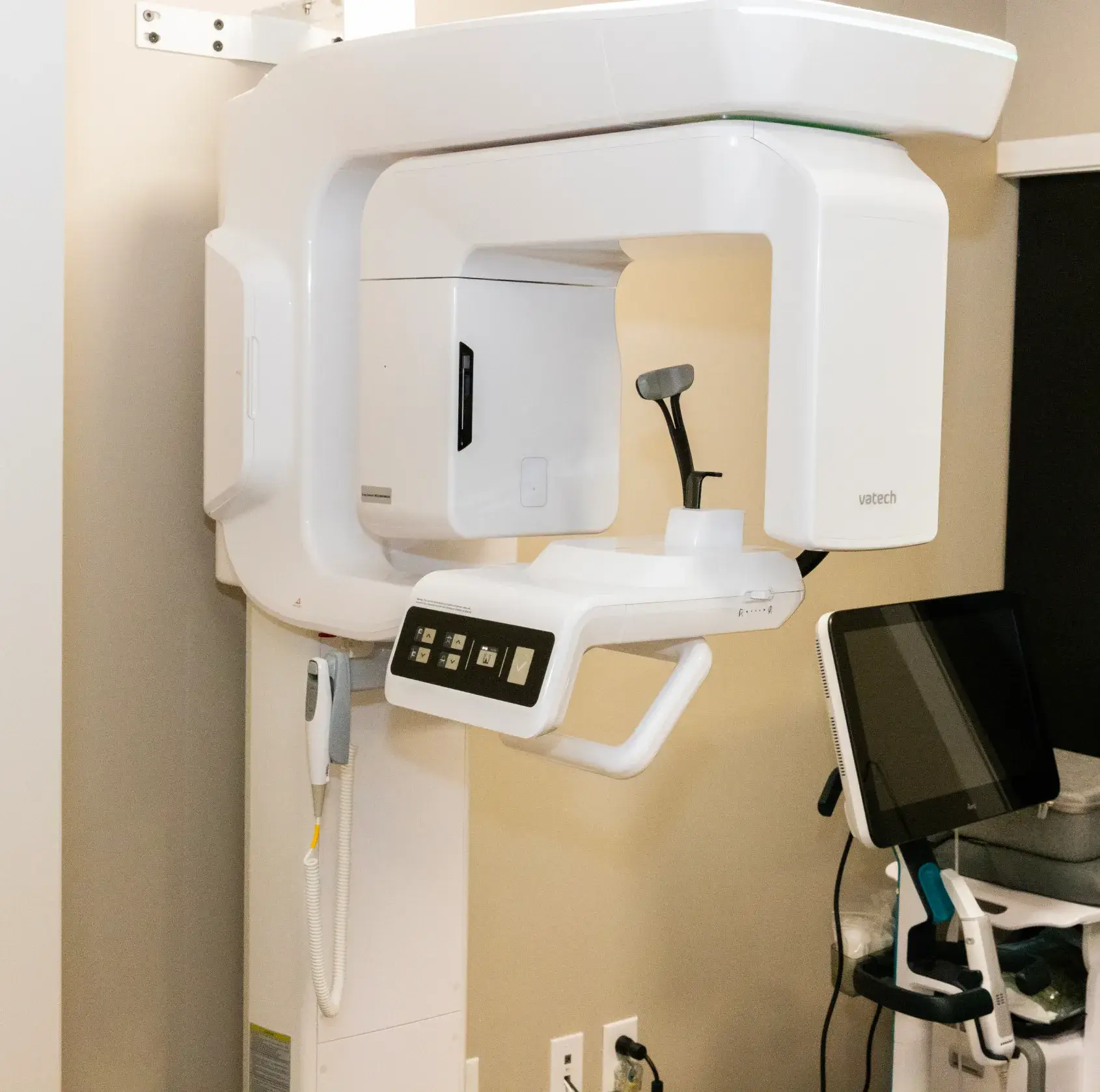 Dental imaging machine next to a computer in a dentist's office.