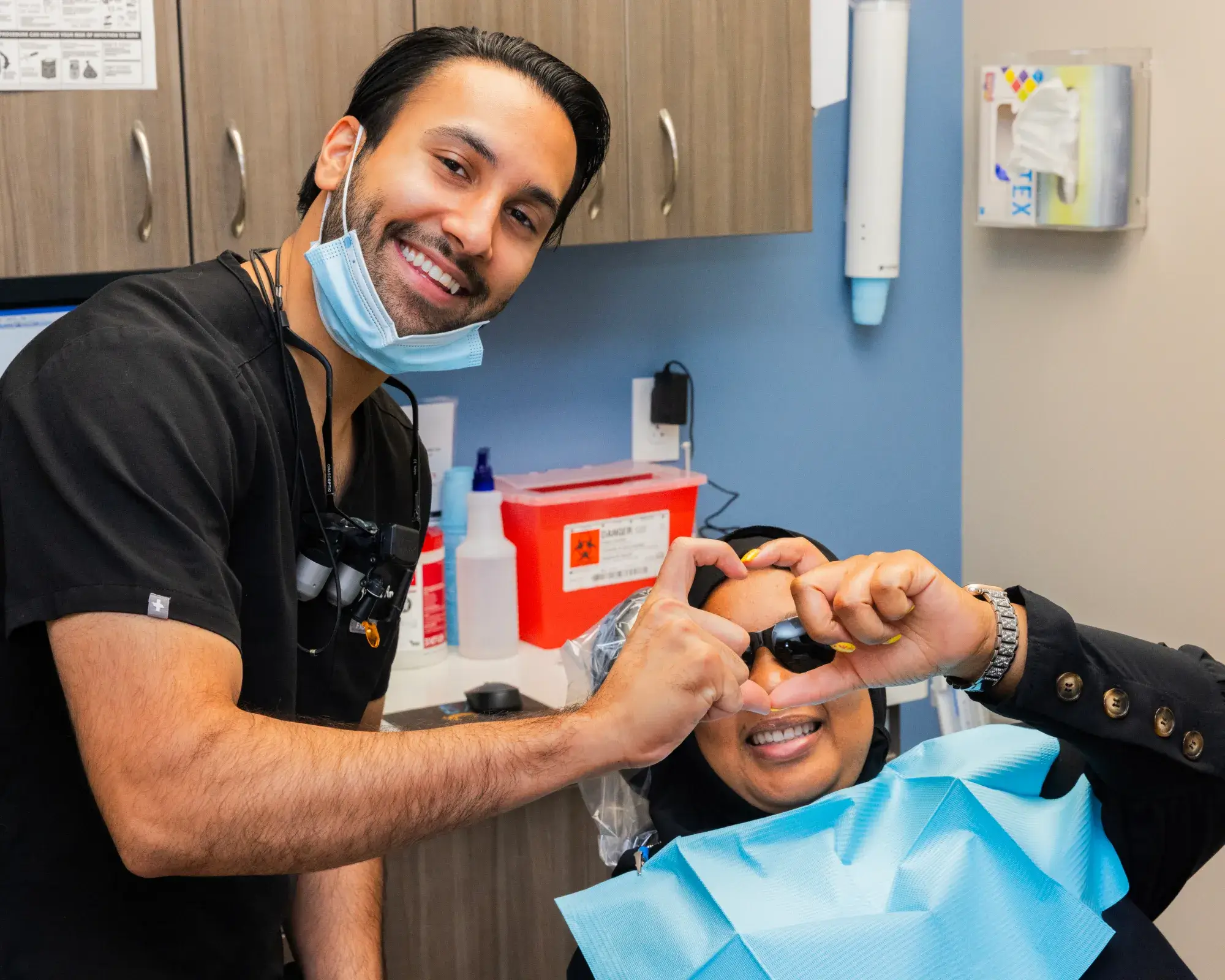 A dentist and patient smile while taking a selfie in a dental office.