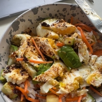 Protein bowl with Umami Everything on a table by a computer.