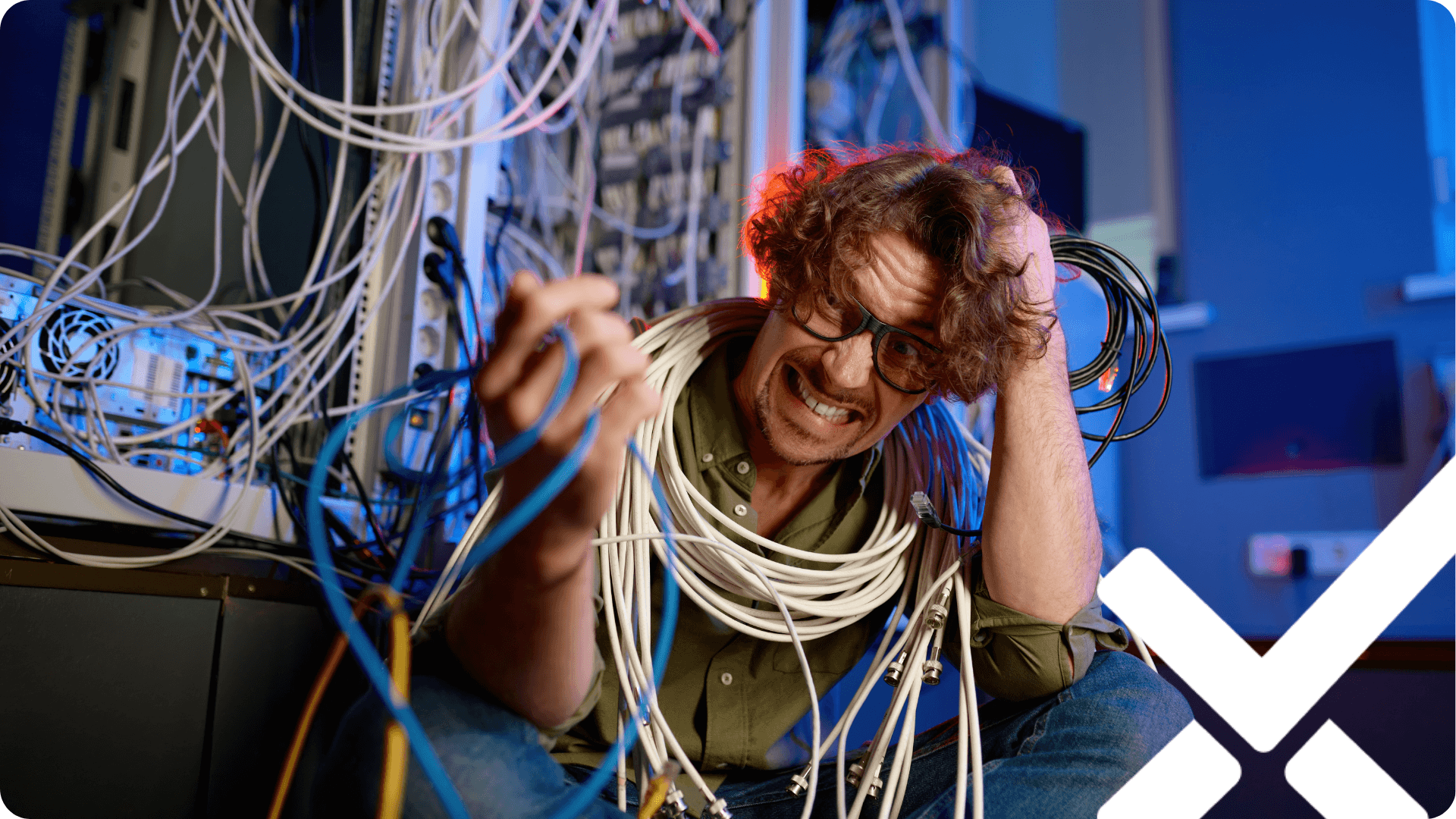 A frustrated employee surrounded by tangled cables in a server room, symbolizing the complexity and headaches of messy, unmanaged spreadsheet systems.