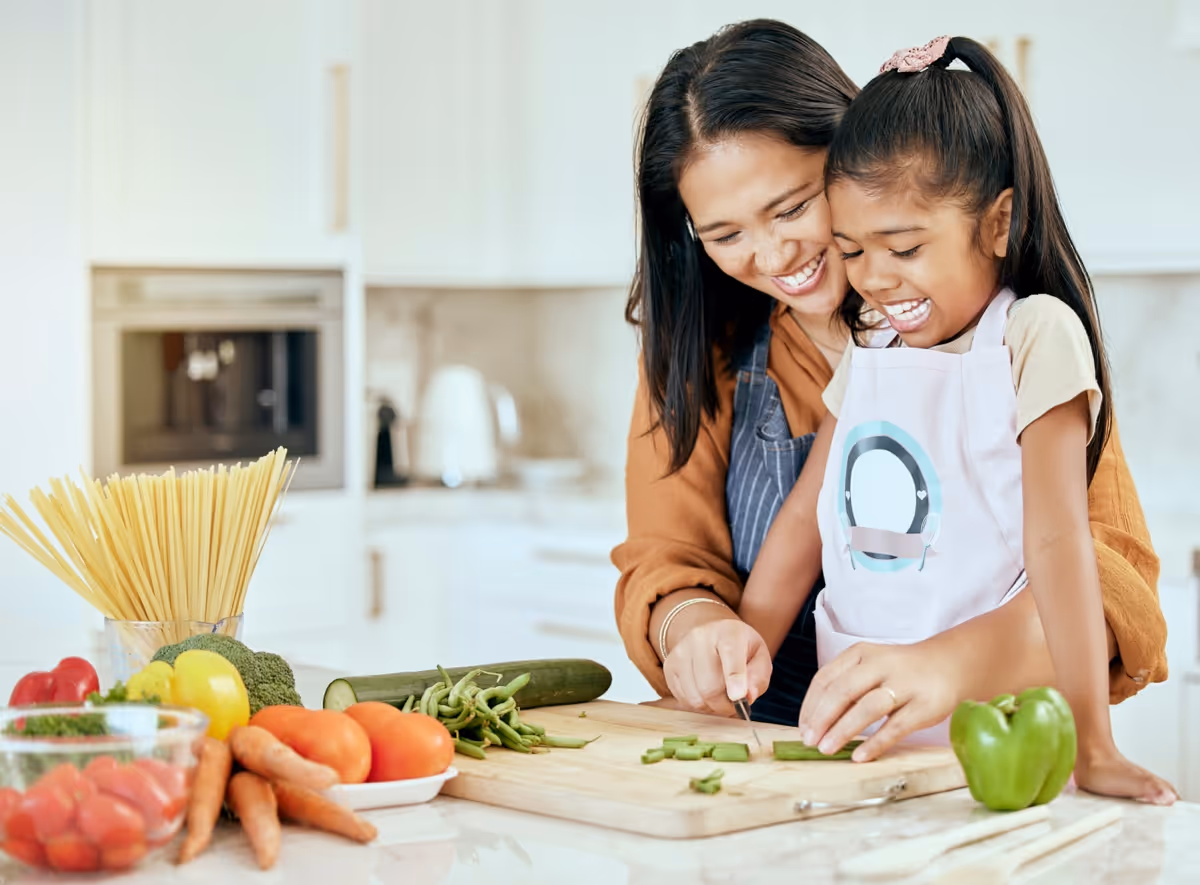 Mother and daughter happily preparing vegetables together in kitchen