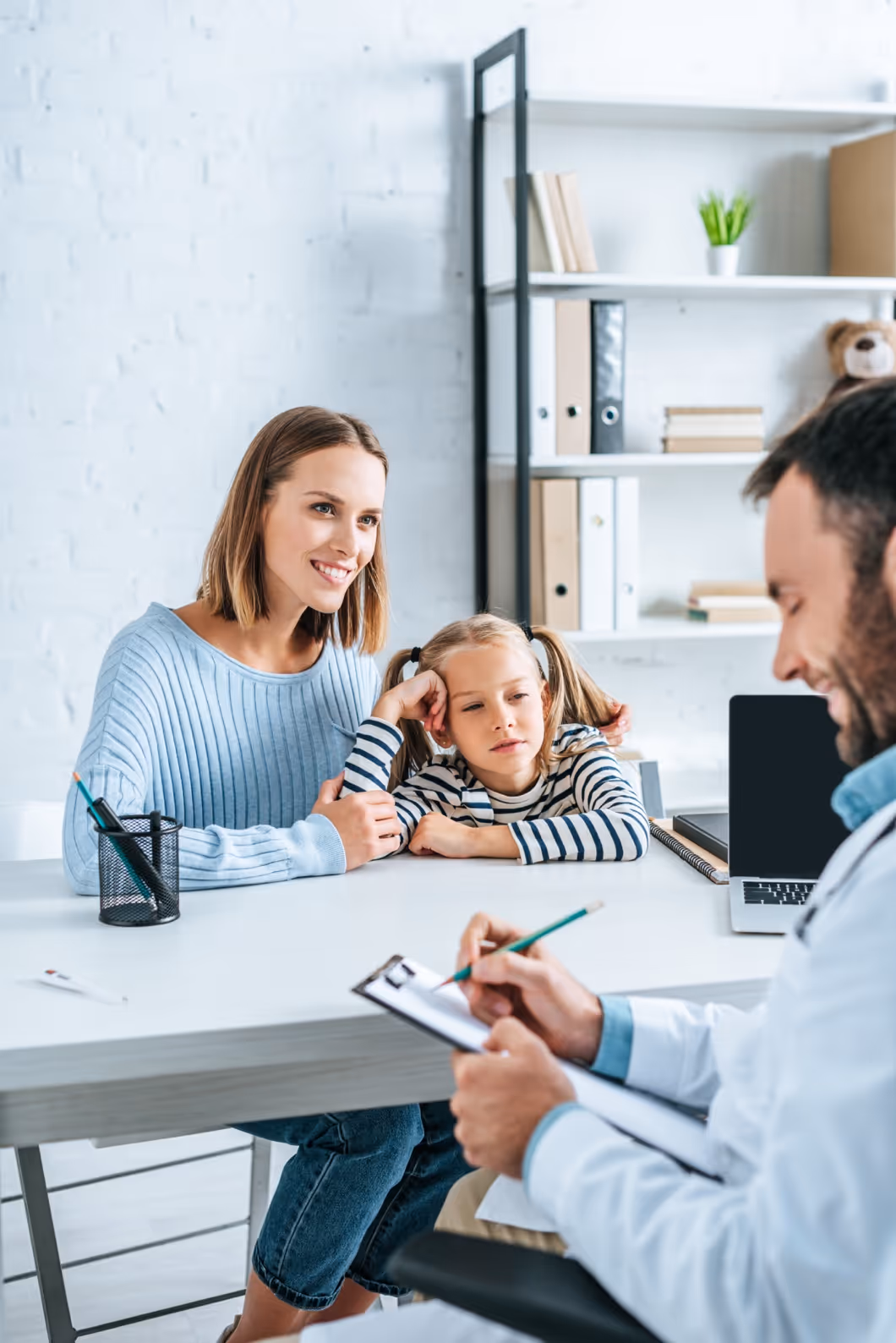 Parent and child meeting with professional in office with bookshelves