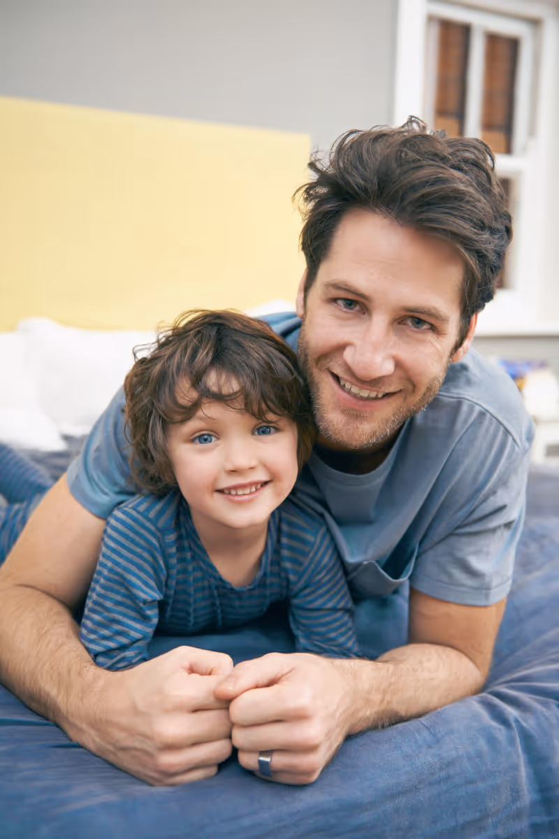 Smiling father and child cuddling together on a blue couch