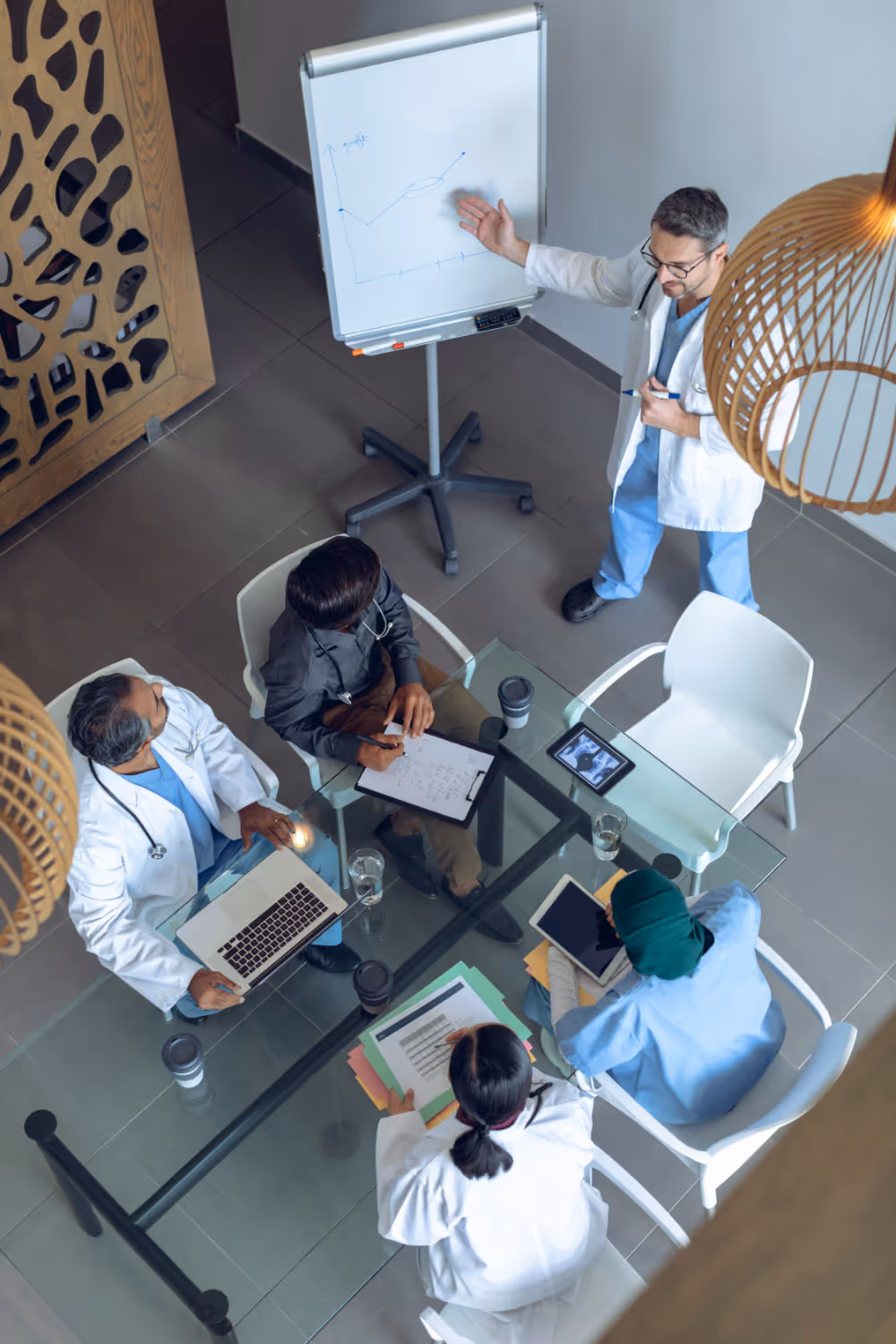 Medical team in meeting, discussing chart on whiteboard from overhead view