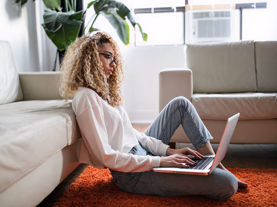 Une femme naviguant sur son ordinateur portable sur son canapé
