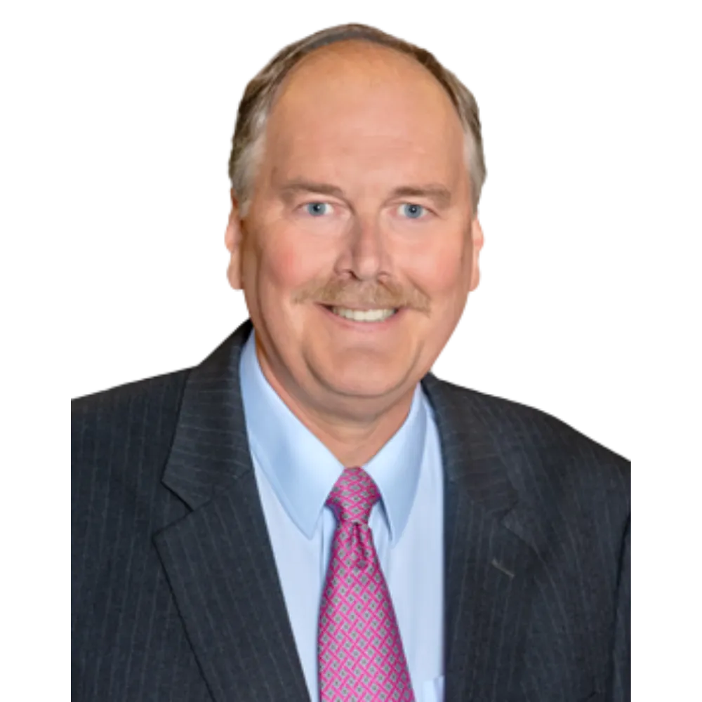 Male headshot smiling at the camera in a dark striped suite with light blue dress shirt and pink tie. 
