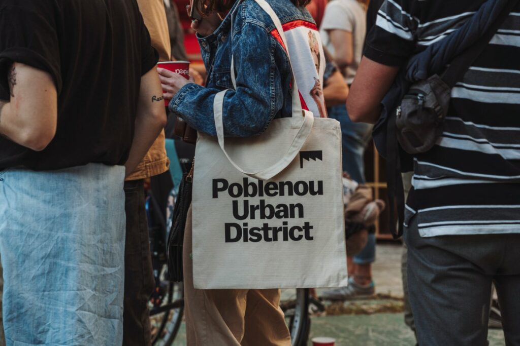 Una chica lleva un bolso de tela con el logo del Poblenou Urban District impreso en él.