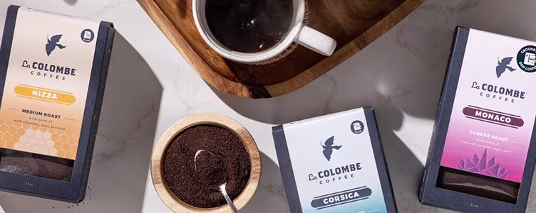 la colombe coffee boxes sitting on a countertop with a coffee mug and coffee grounds