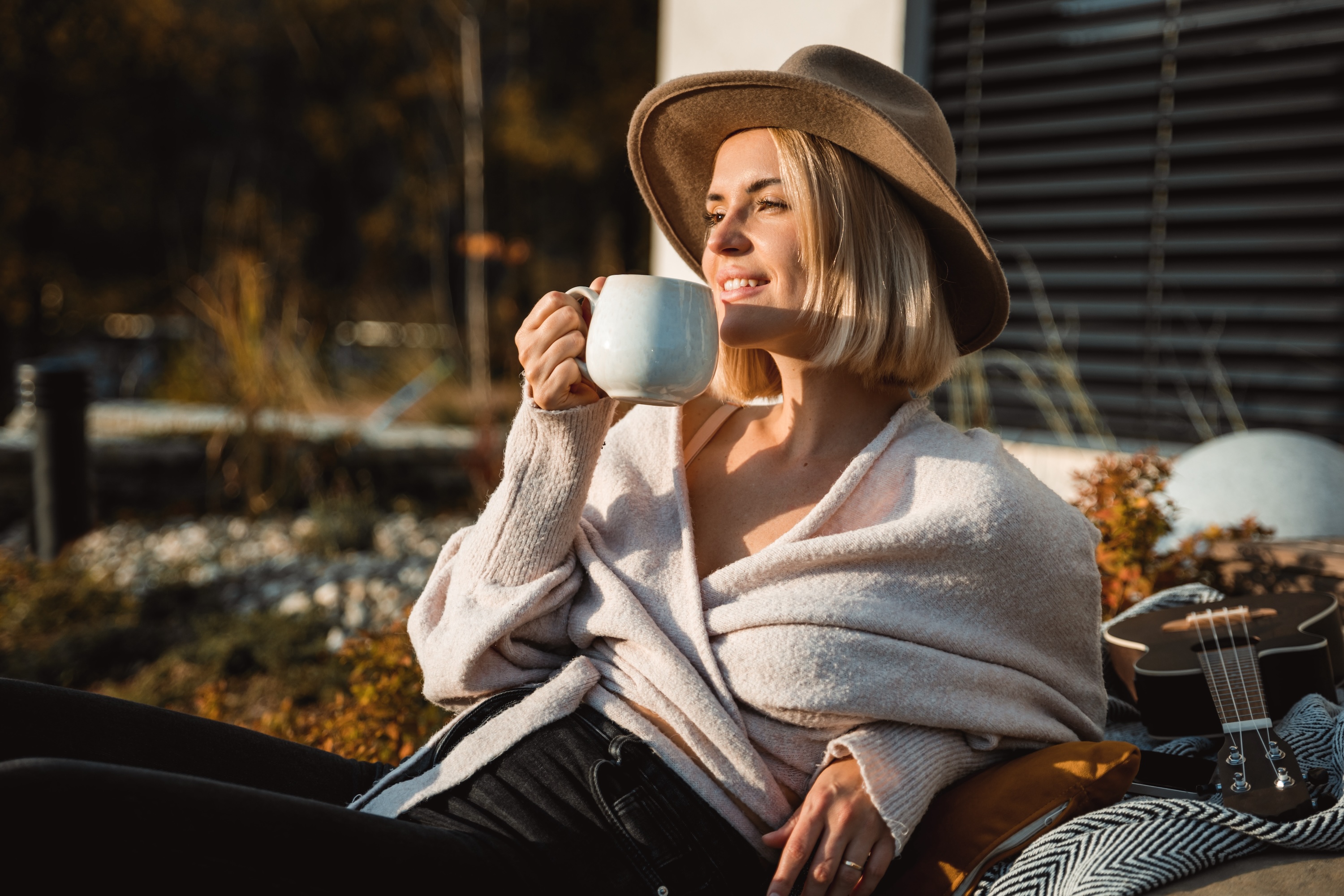 Resident relaxing on a sun-drenched patio with coffee at The Eleanor Daytona Beach, highlighting luxury outdoor amenities and coastal living in Daytona Beach, FL.