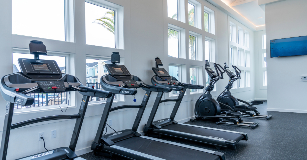 State-of-the-art fitness center with a variety of cardio machines, weights, and high ceilings, available for residents at The Eleanor Daytona Beach in Daytona Beach, Florida.