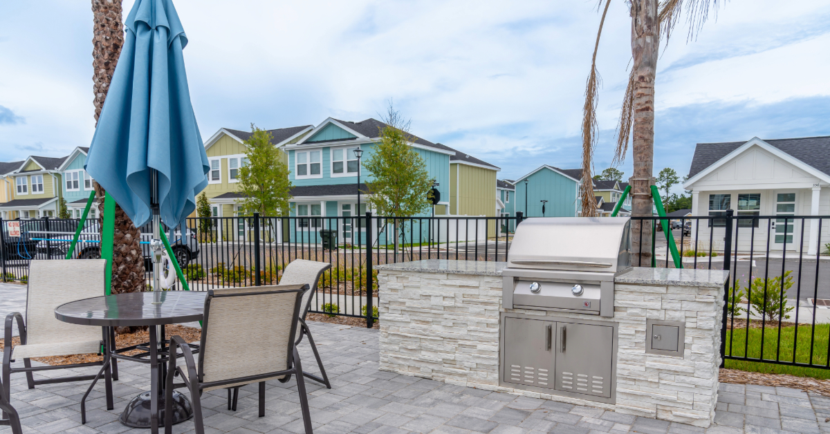Resident clubhouse lounge with various seating options, modern light fixtures, and a view of the pool area at The Eleanor Daytona Beach in Daytona Beach, Florida.