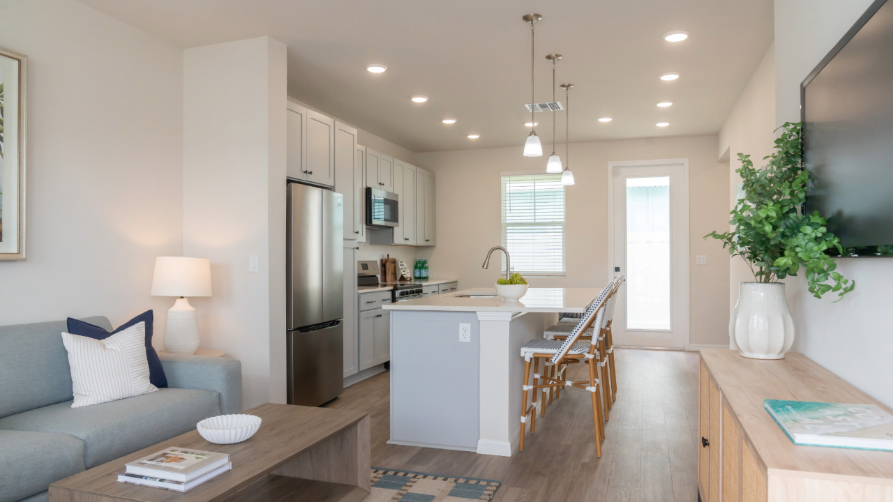 Spacious open-concept living and dining area with a modern sofa, round table, and ceiling fan at The Eleanor Daytona Beach in Daytona Beach, Florida.