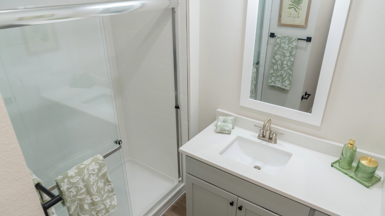 Contemporary bathroom with a dual vanity, light wood cabinets, and modern black fixtures, in a home at The Eleanor Daytona Beach in Daytona Beach, Florida.