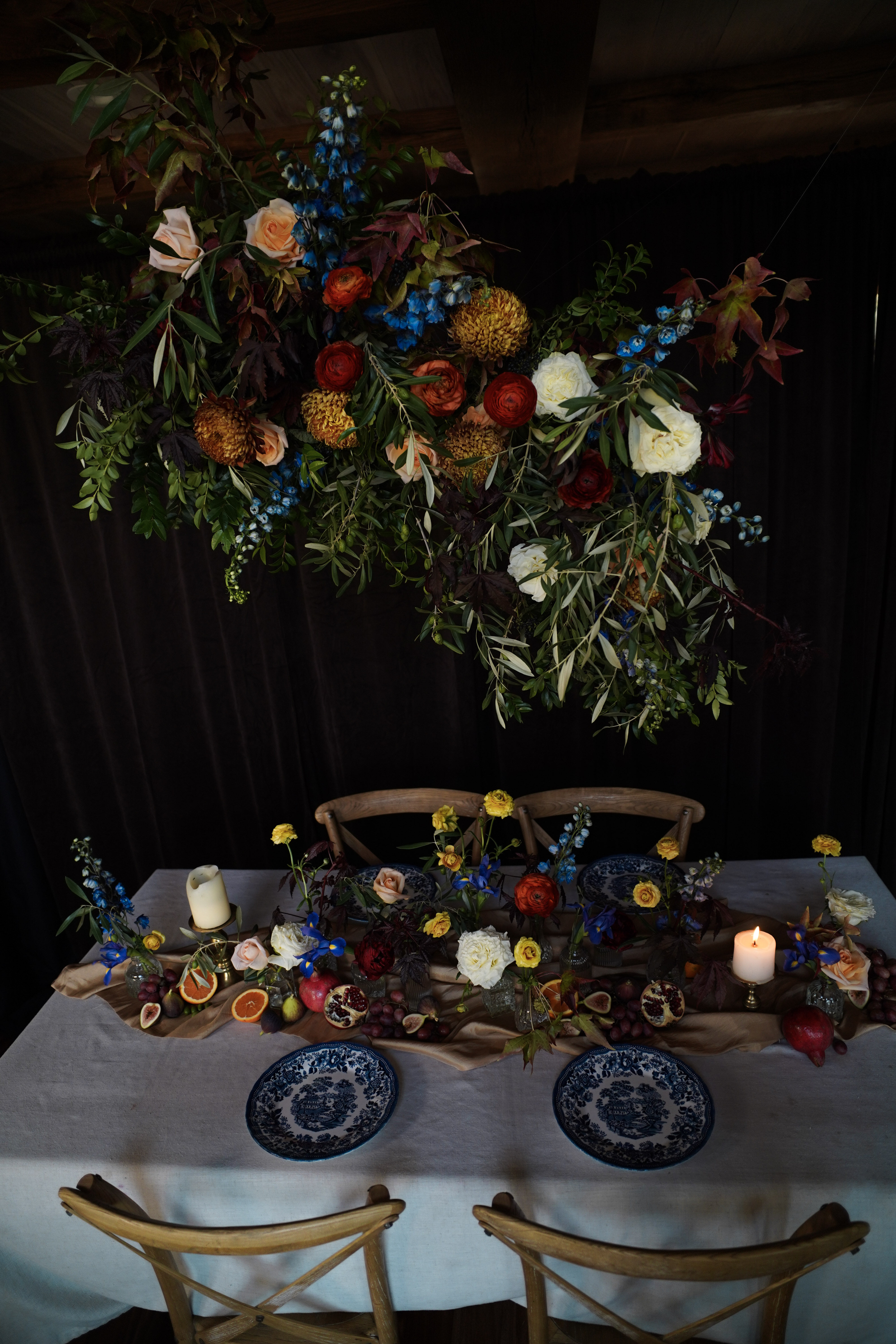 Dutch art inspired floral installation and tablescape in rich colors, set for a wedding reception or corporate event somewhere in Middle Tennessee.