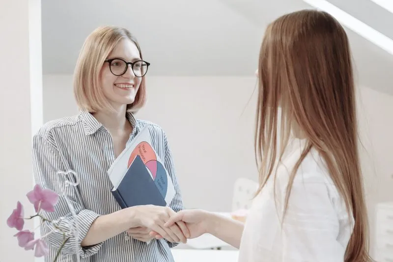 Blonde and red head women shaking hands