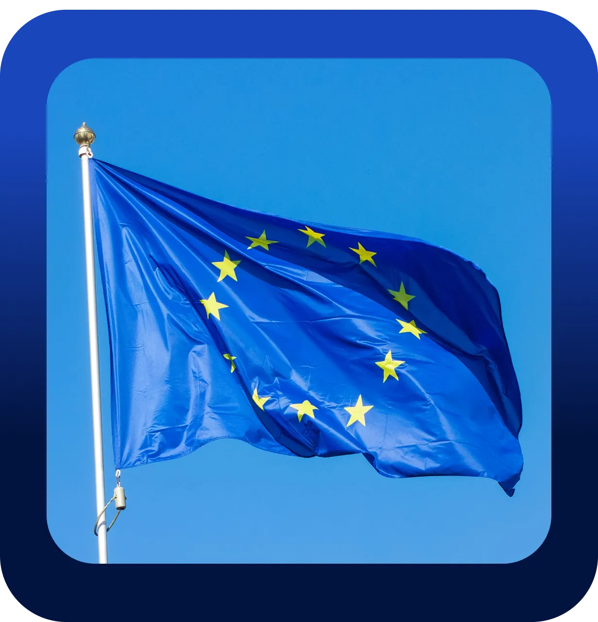 European Union flag with yellow stars arranged in a circle on a blue background, waving on a flagpole against a clear blue sky.