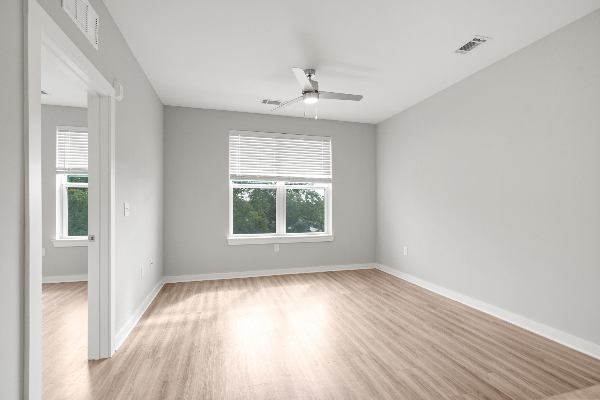 Unfurnished living area with ceiling fan and large windows