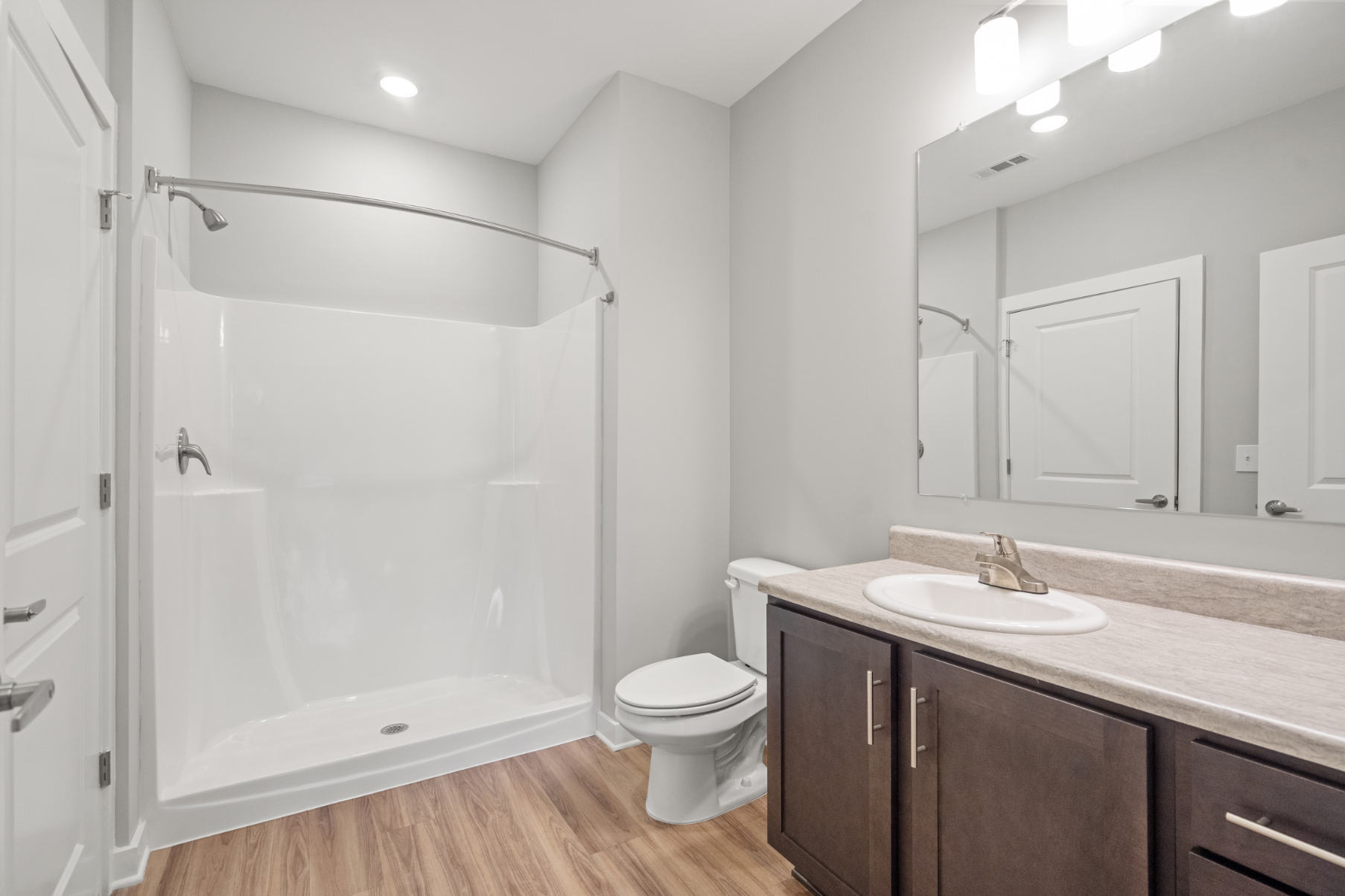 Bathroom with brown cabinets, vanity, and large shower