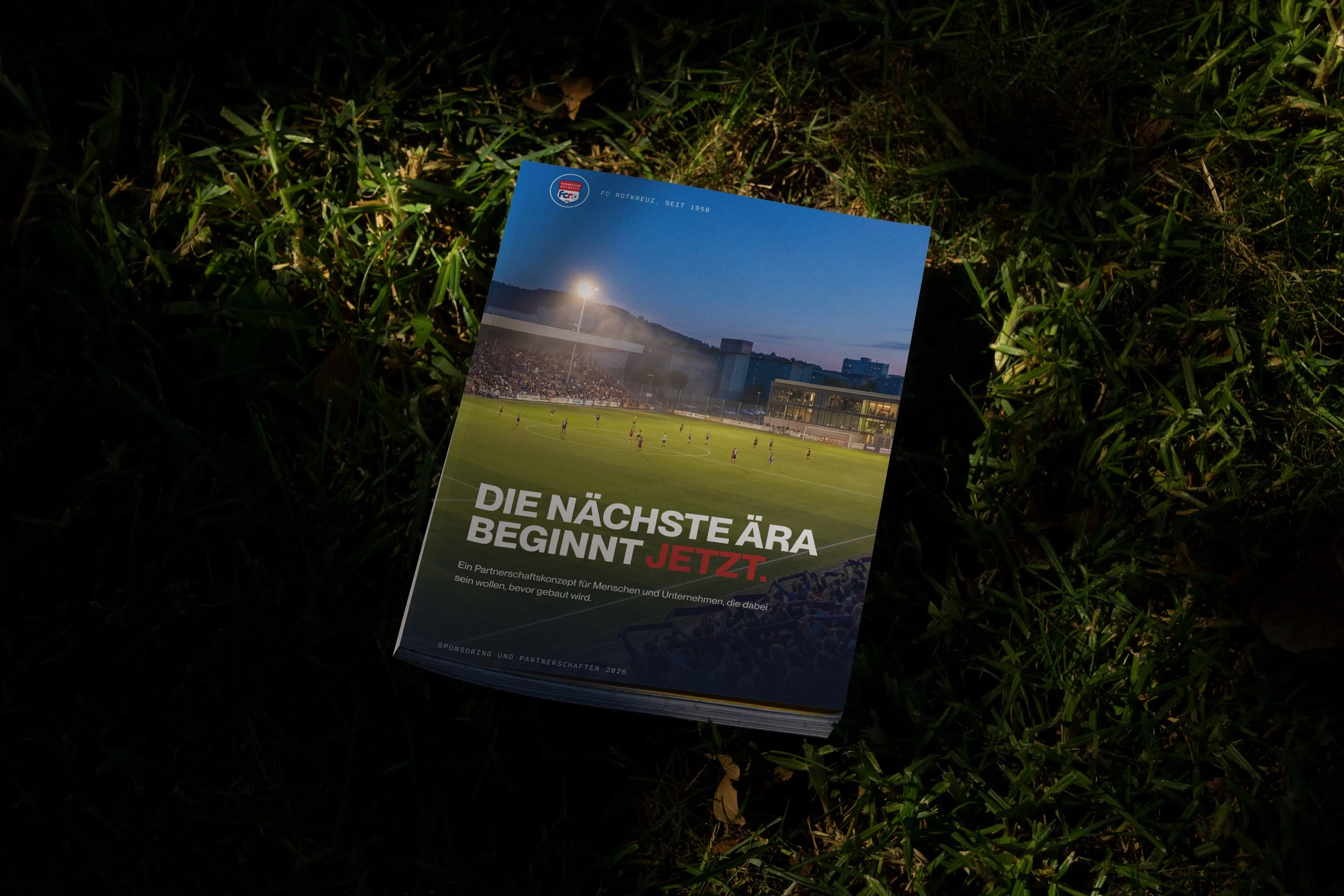The FC Rotkreuz sponsoring dossier lying on the pitch at night