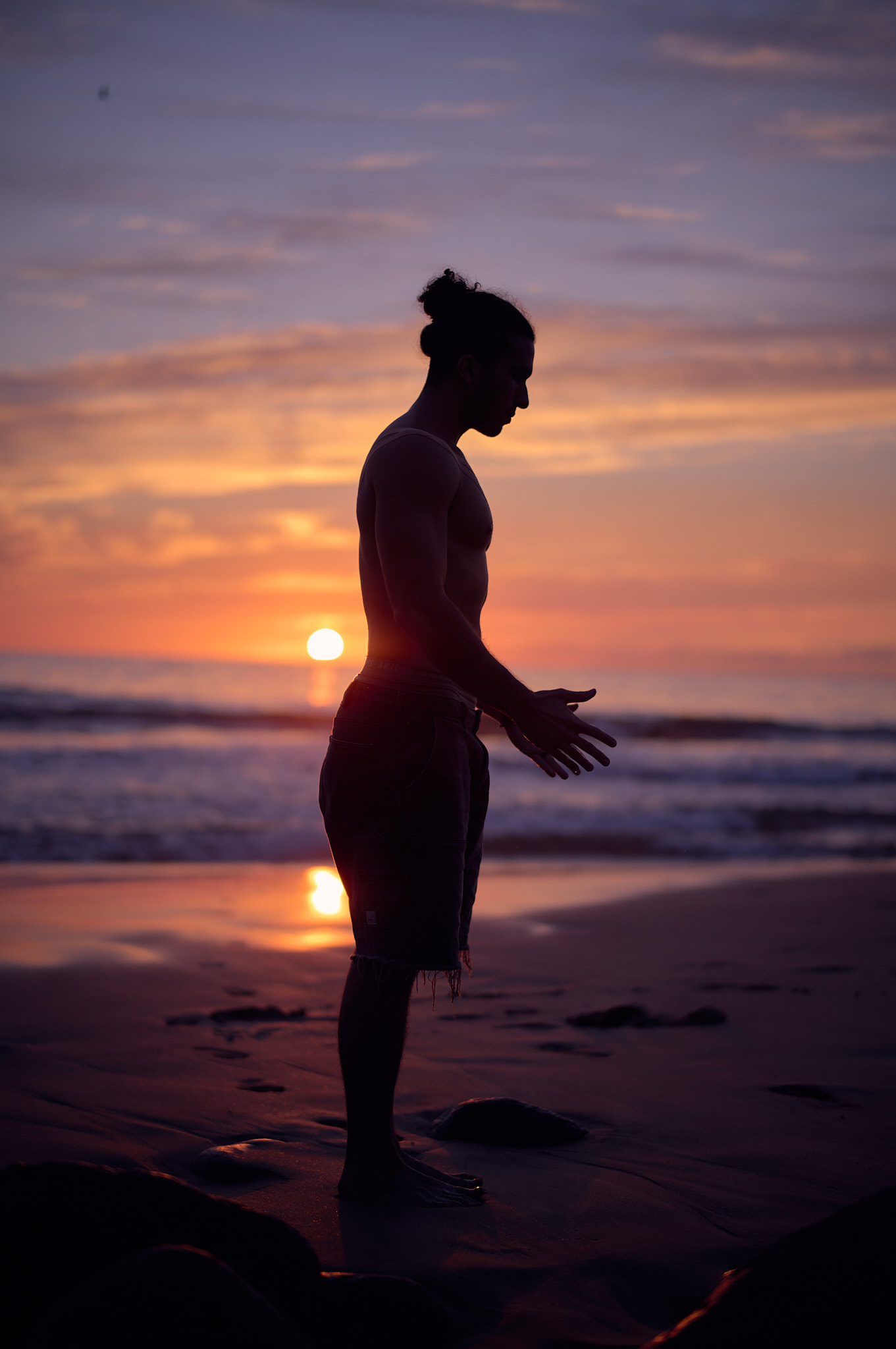 Jonah Kest stands in silent meditation on the wet sand as the sun dips into the Pacific.