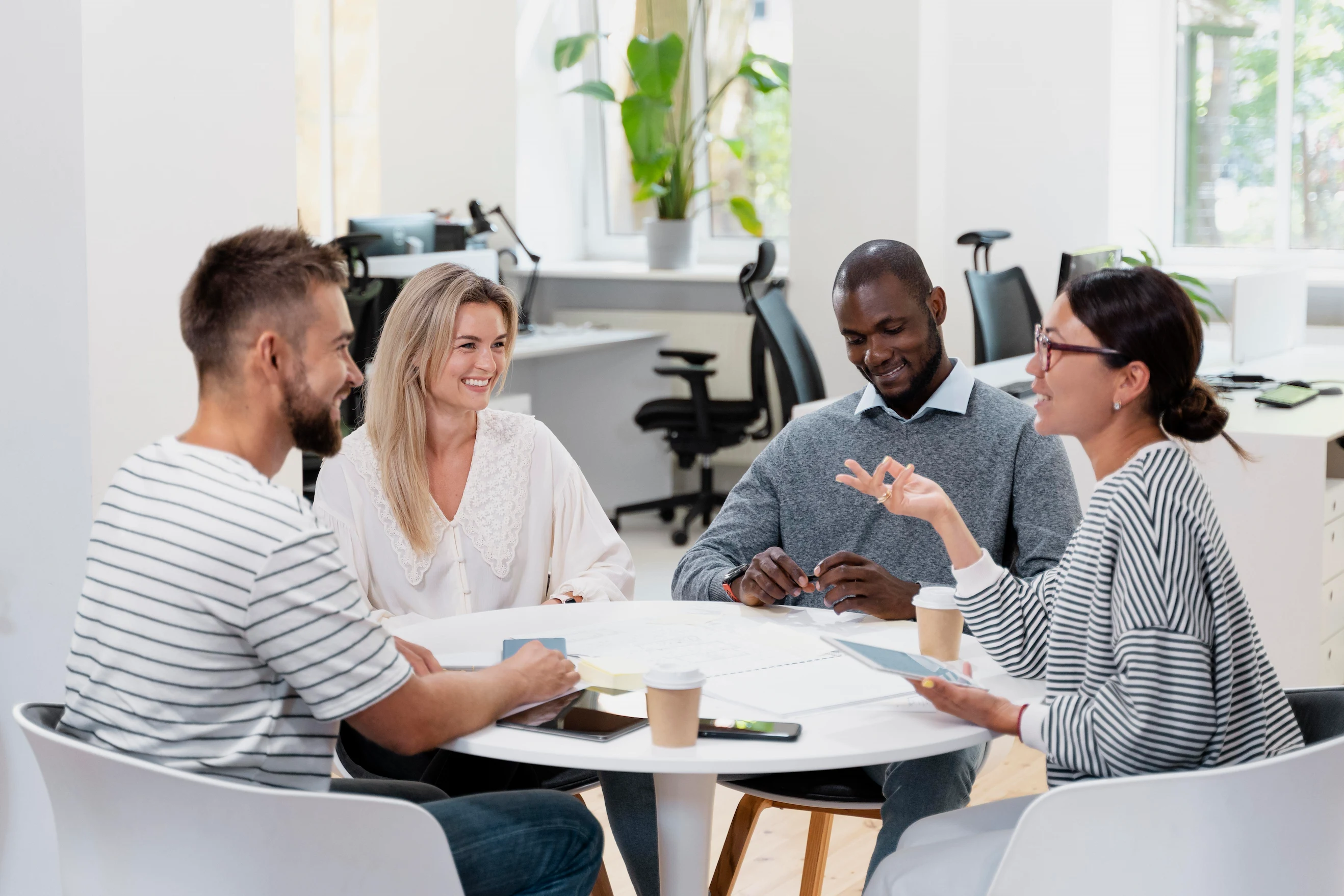A group of colleagues gathered at a table, participating in a meeting within an office space.