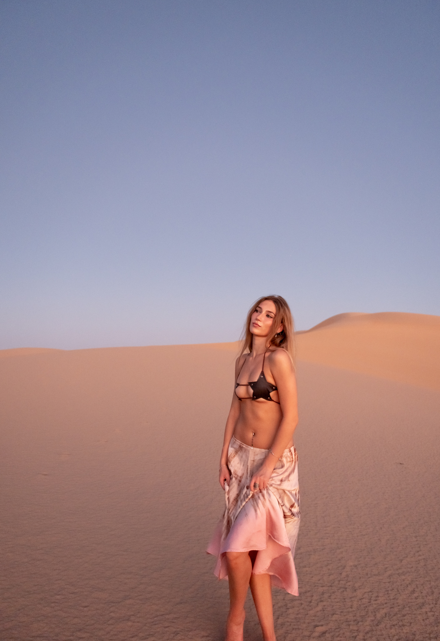 Fashion lifestyle portrait of model wearing outfit in sand dunes.