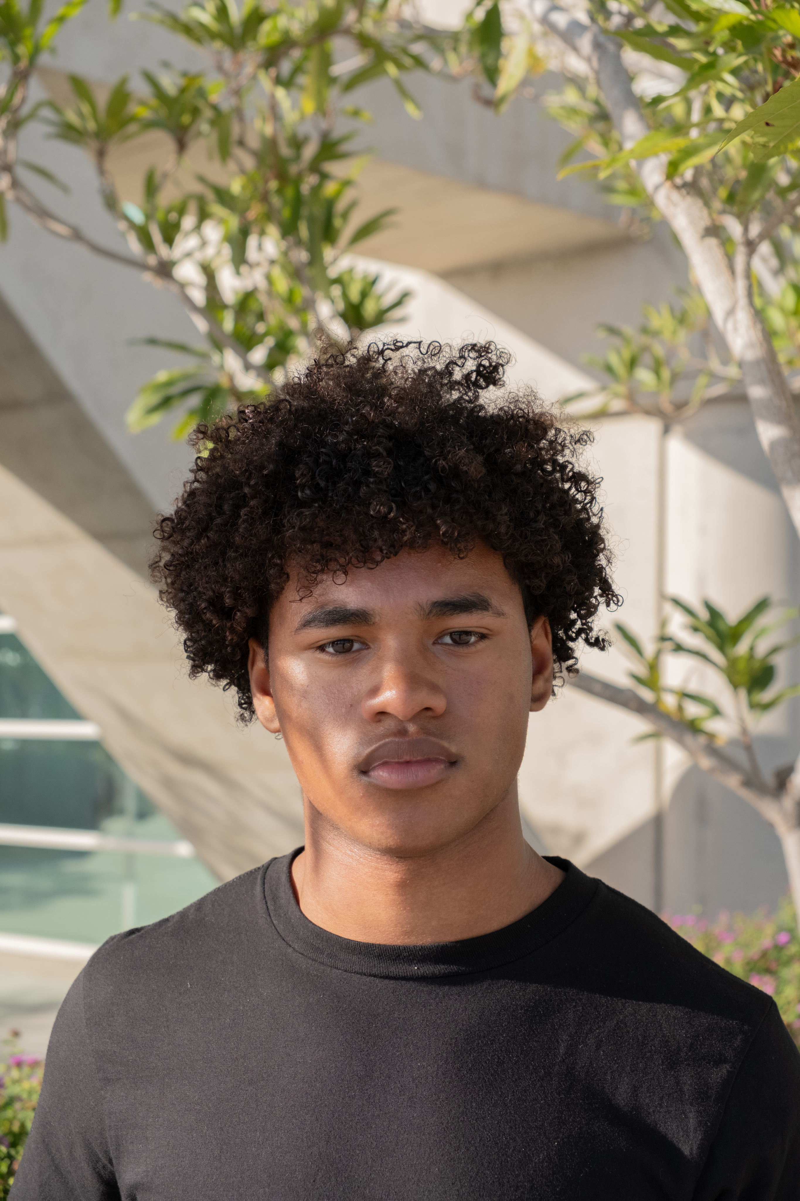 Outdoor portrait of a model in a black T-shirt beside pale concrete architecture
