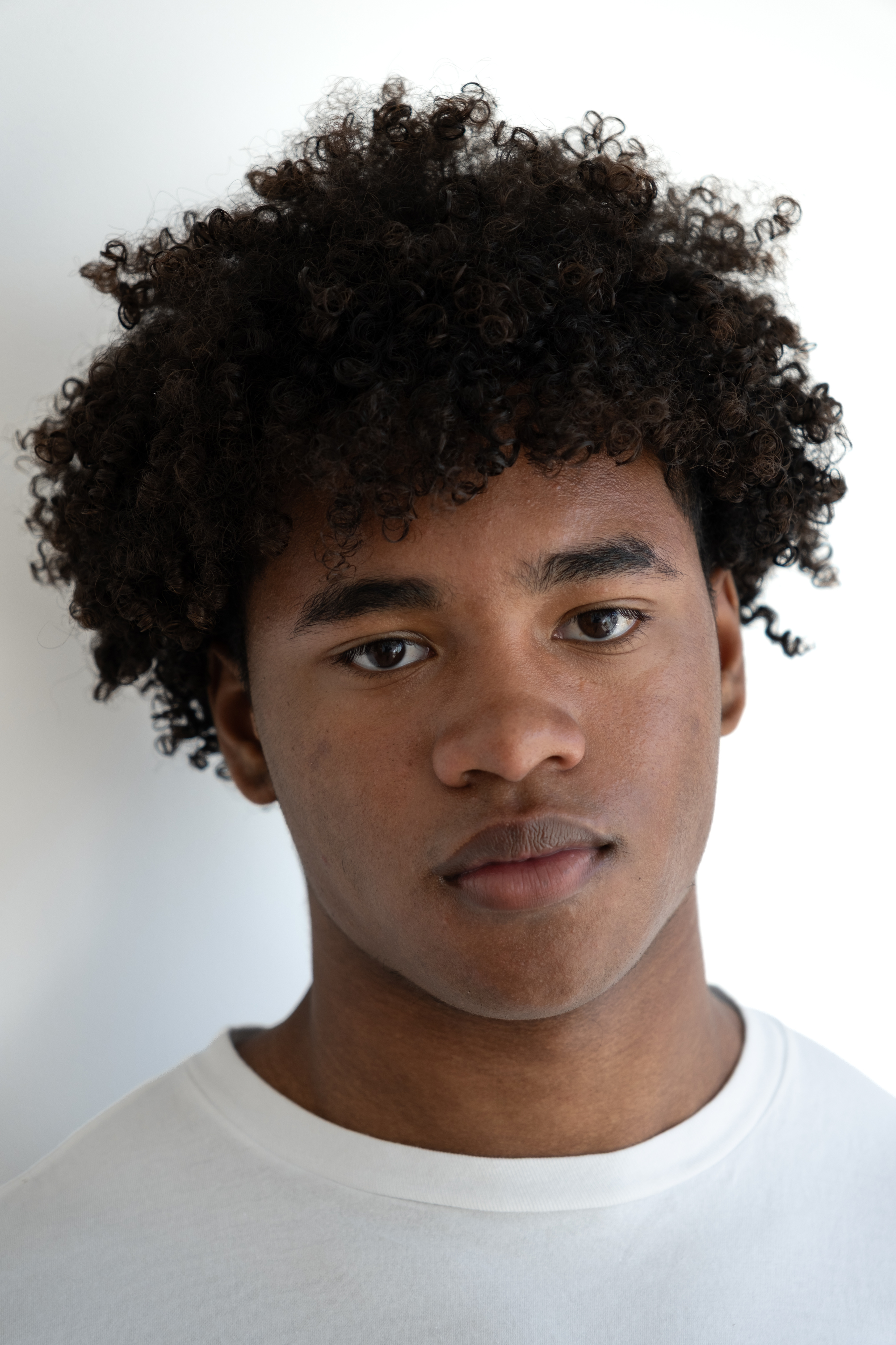 Right-facing three-quarter headshot in a white T-shirt against a plain white background.