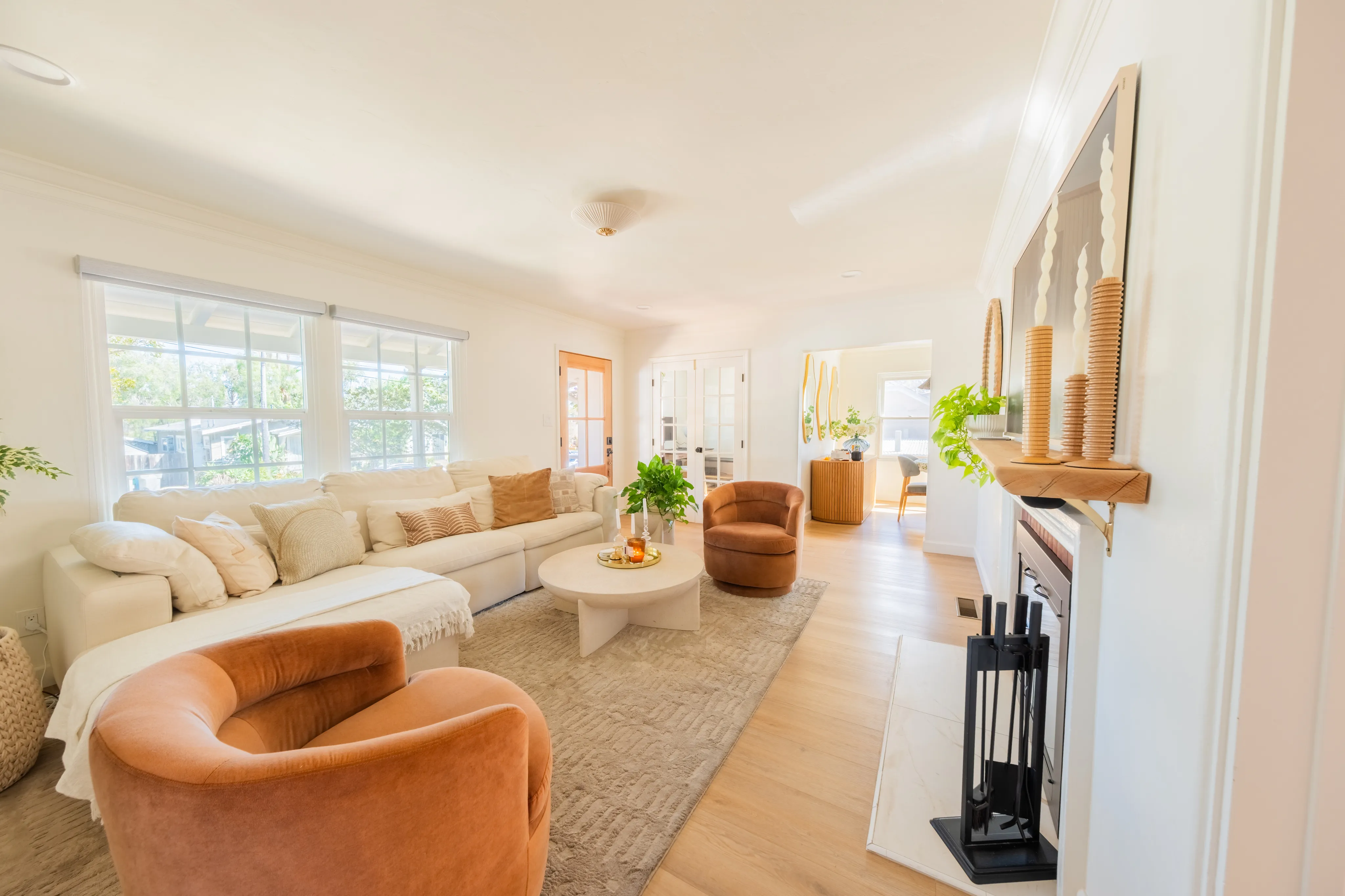 Bright living room with a cream sectional, warm-toned chairs and a fireplace.