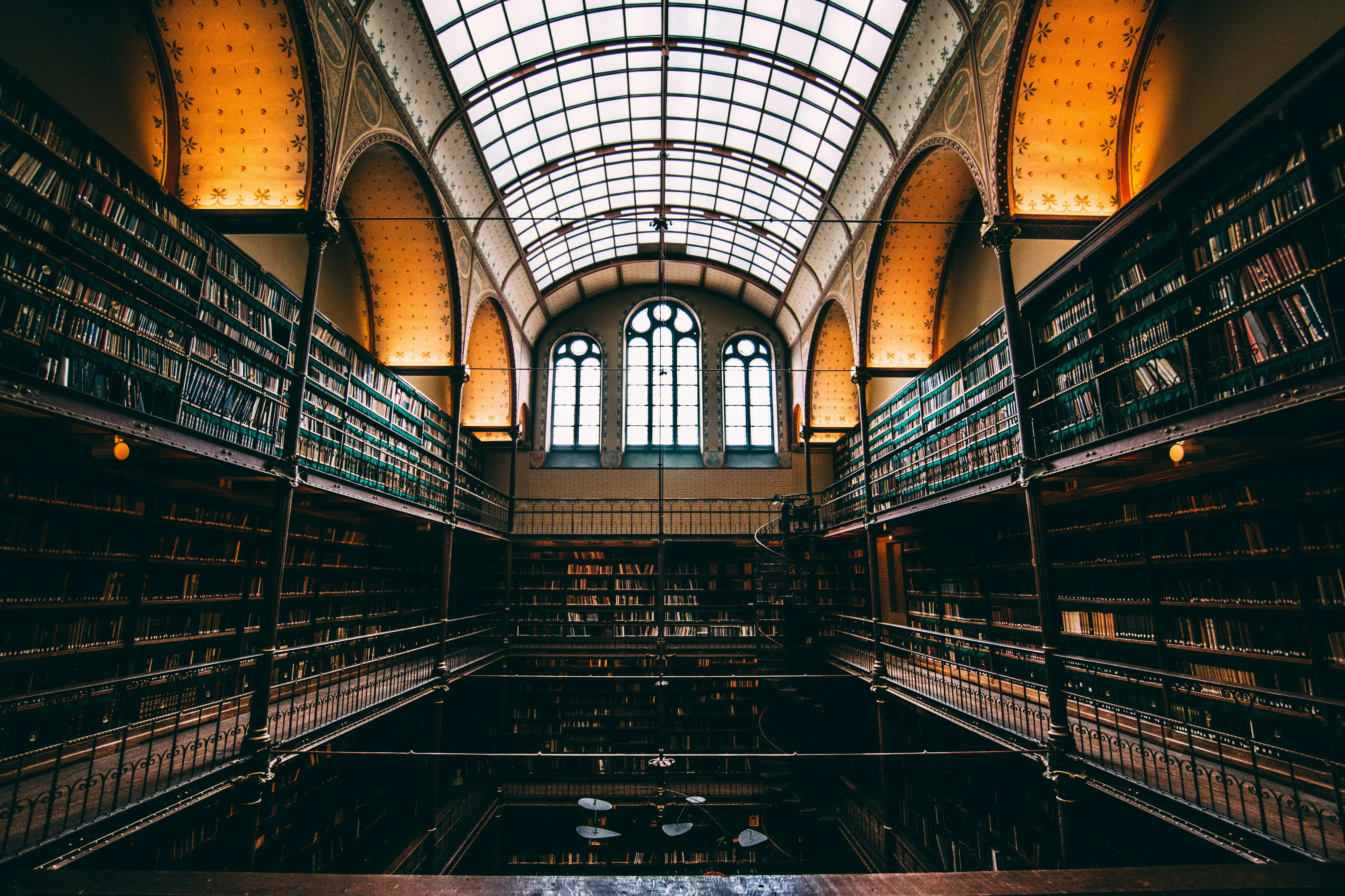 Elegant historic library with ornate glass ceiling and floor-to-ceiling bookshelves