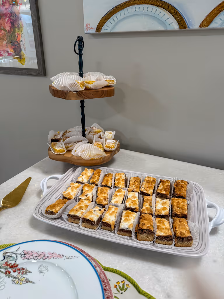 Plated s’mores bars with marshmallow topping and a tiered stand of lemon bars — by Villani’s Bakery.
