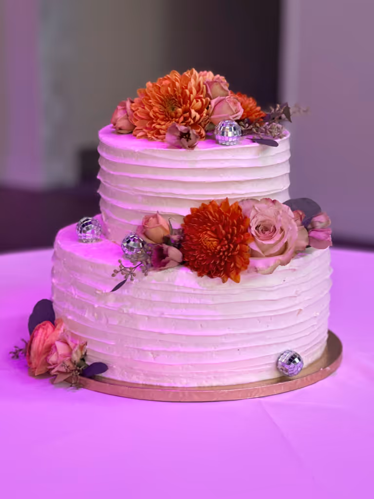 Two-tier white buttercream cake with orange and pink flowers by Villani's Bakery