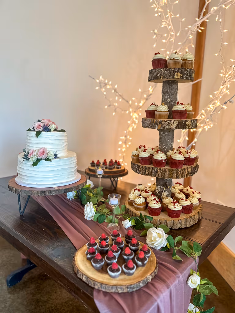 Rustic wedding dessert table with two-tier cake and wooden cupcake tower by Villani's Bakery