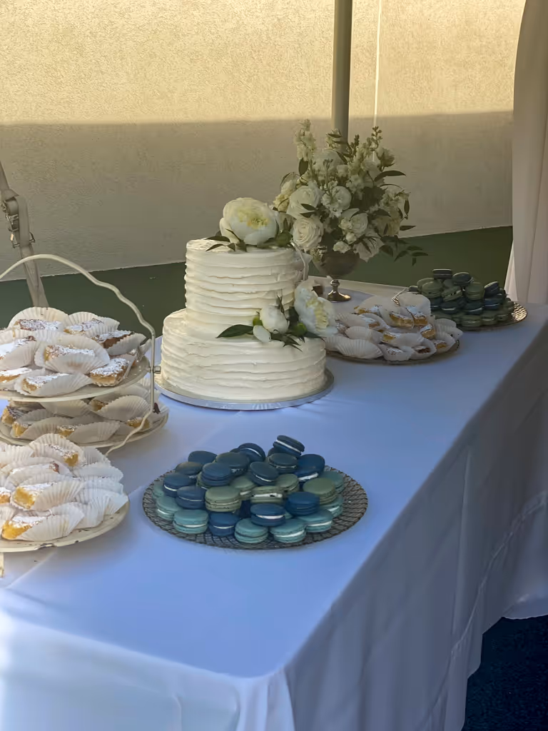 Wedding dessert table with two-tier white cake and assorted macarons by Villani's Bakery
