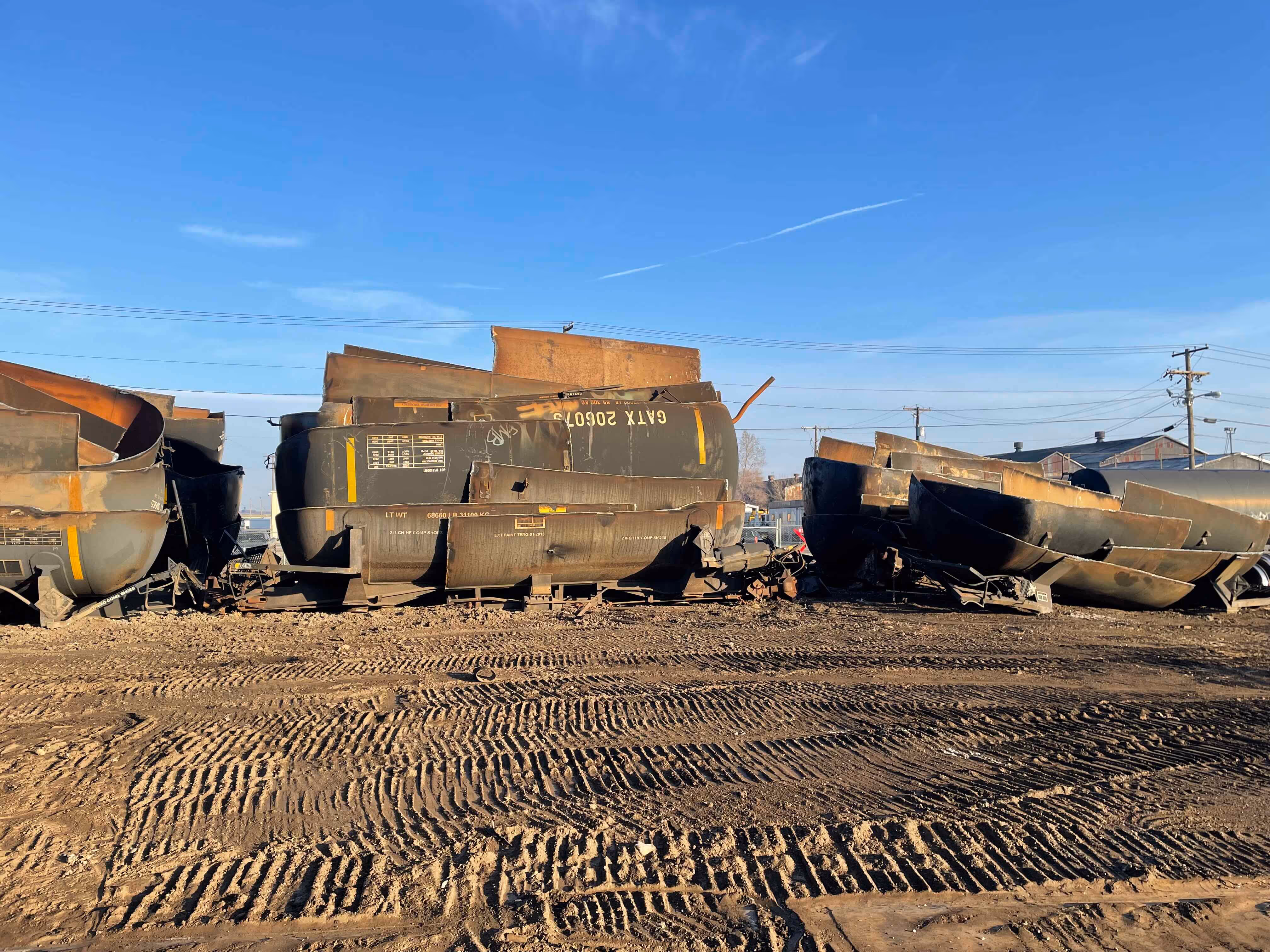 A pile of old railroad cars resting on a dirt surface, showcasing rust and wear from years of disuse.