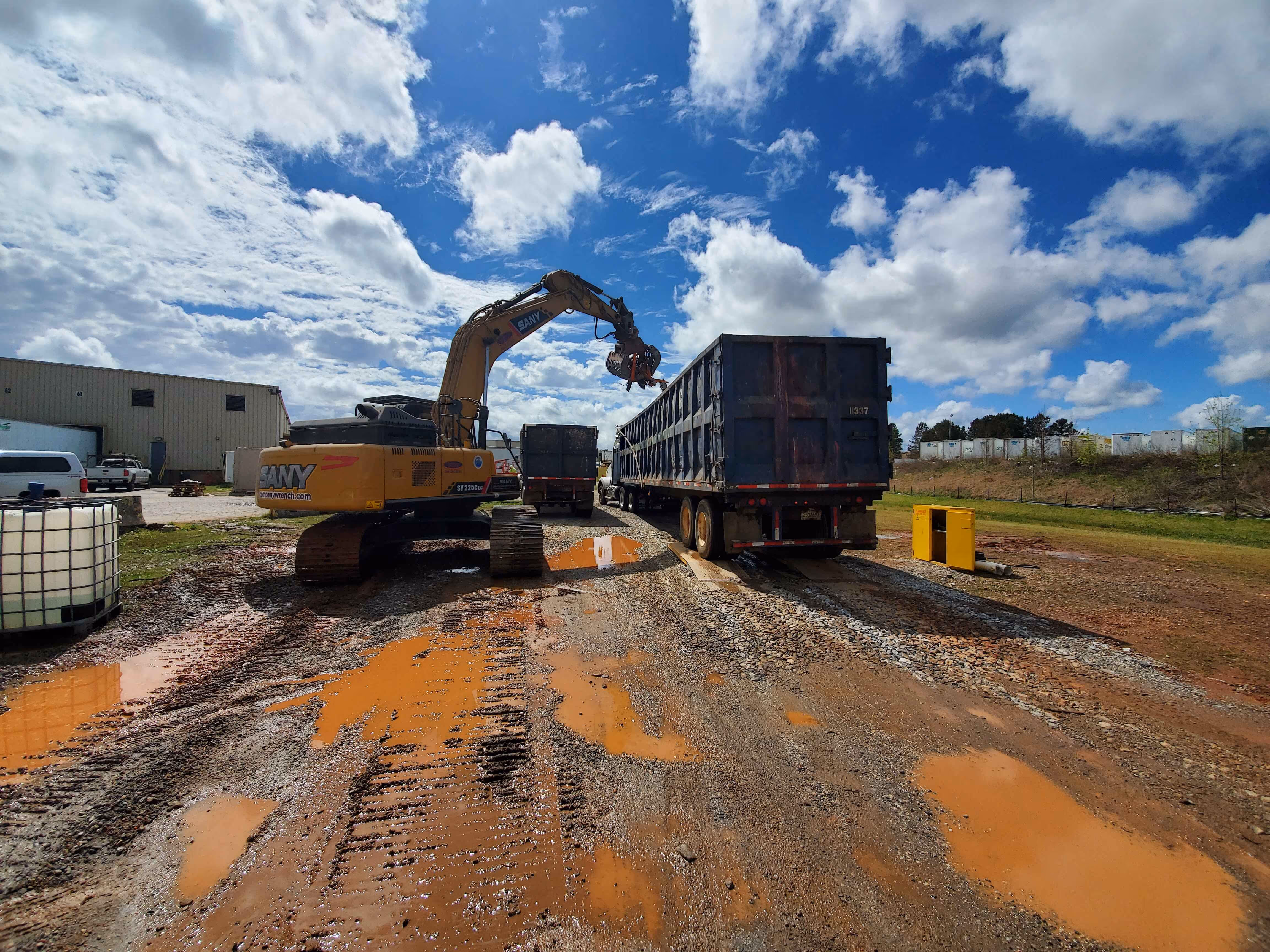 A digger moving debris and scraps into a truck.