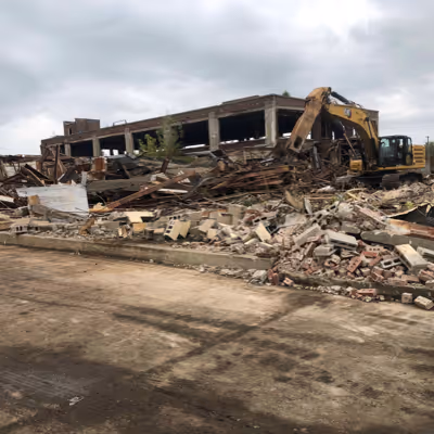 A digger next to a house being destroyed.