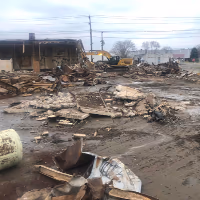 Debris laying in a baron area with a digger cleaning it up.