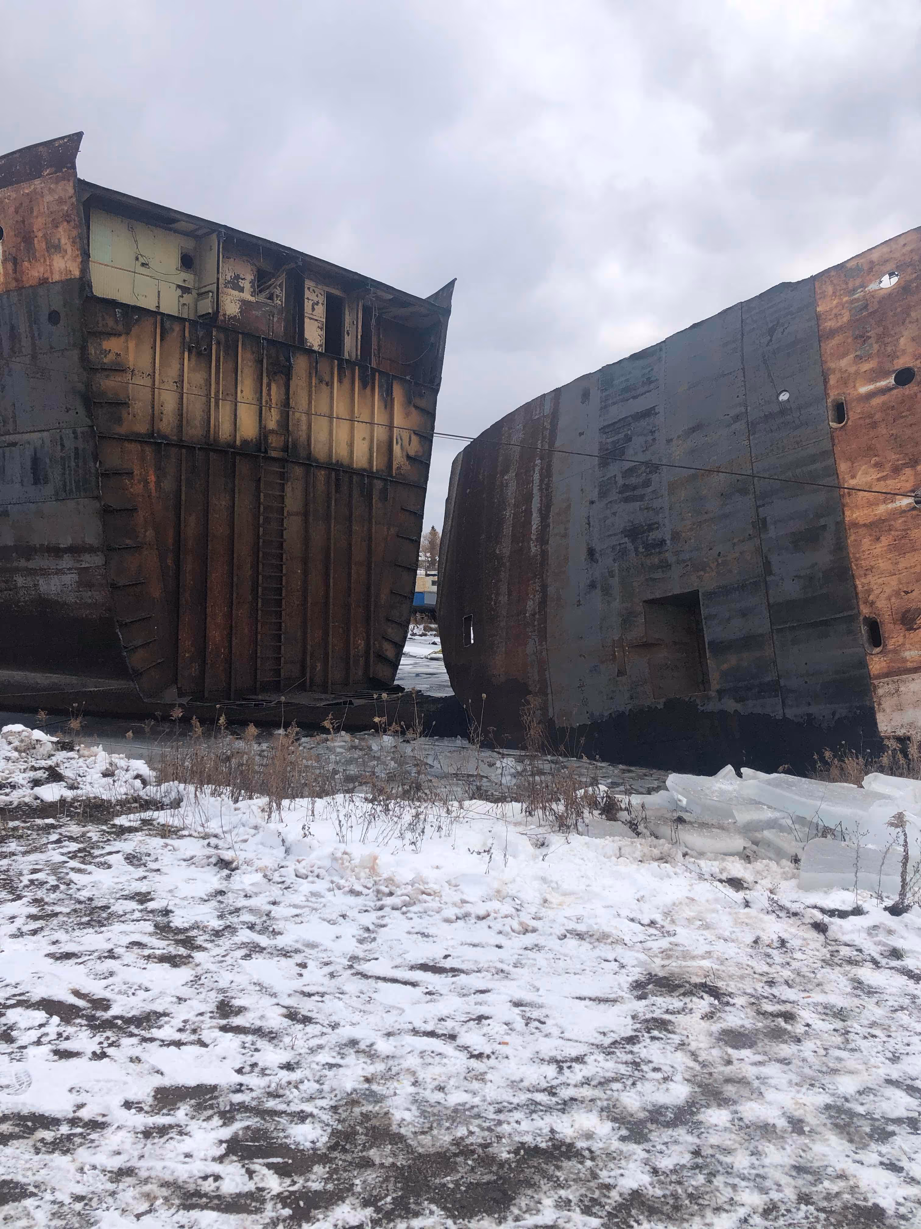 Rusted ship parts sitting on land. 