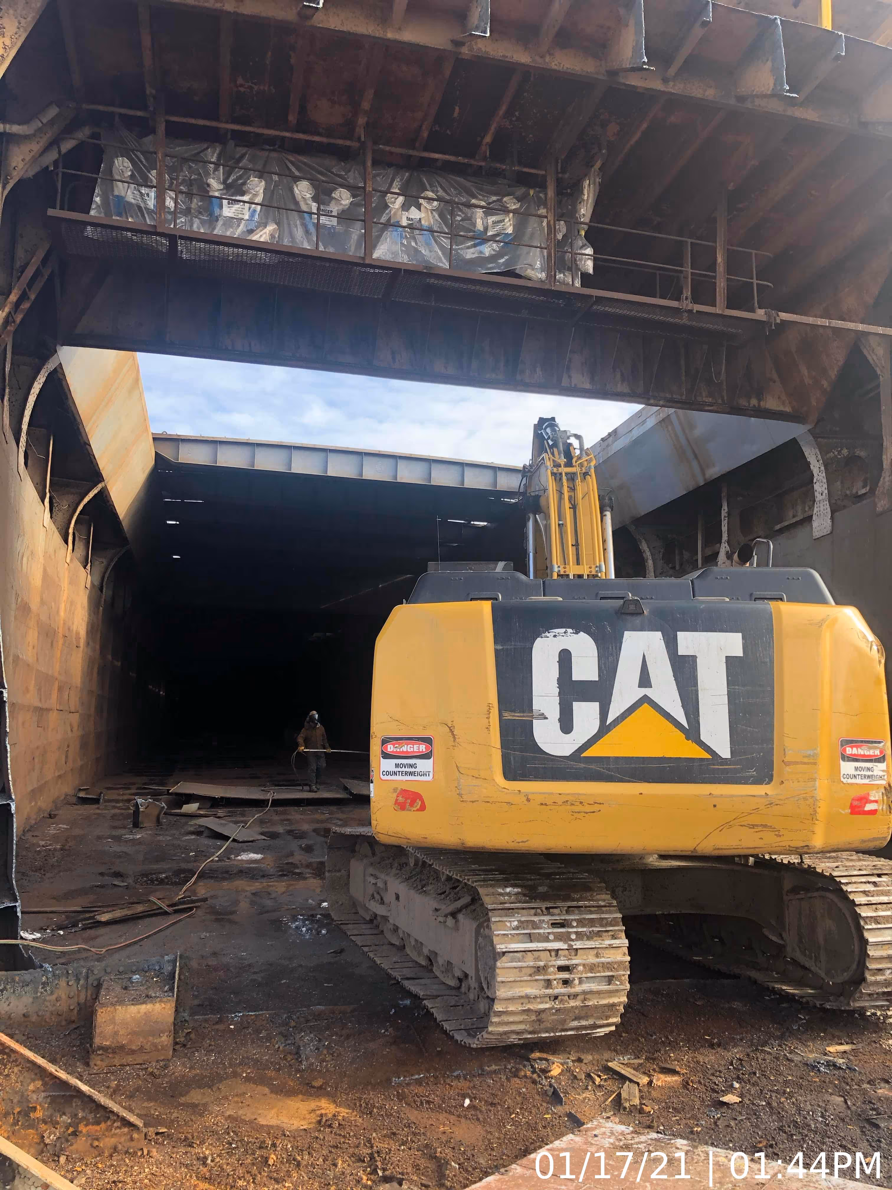 A CAT digger working on deconstructing a large ship.