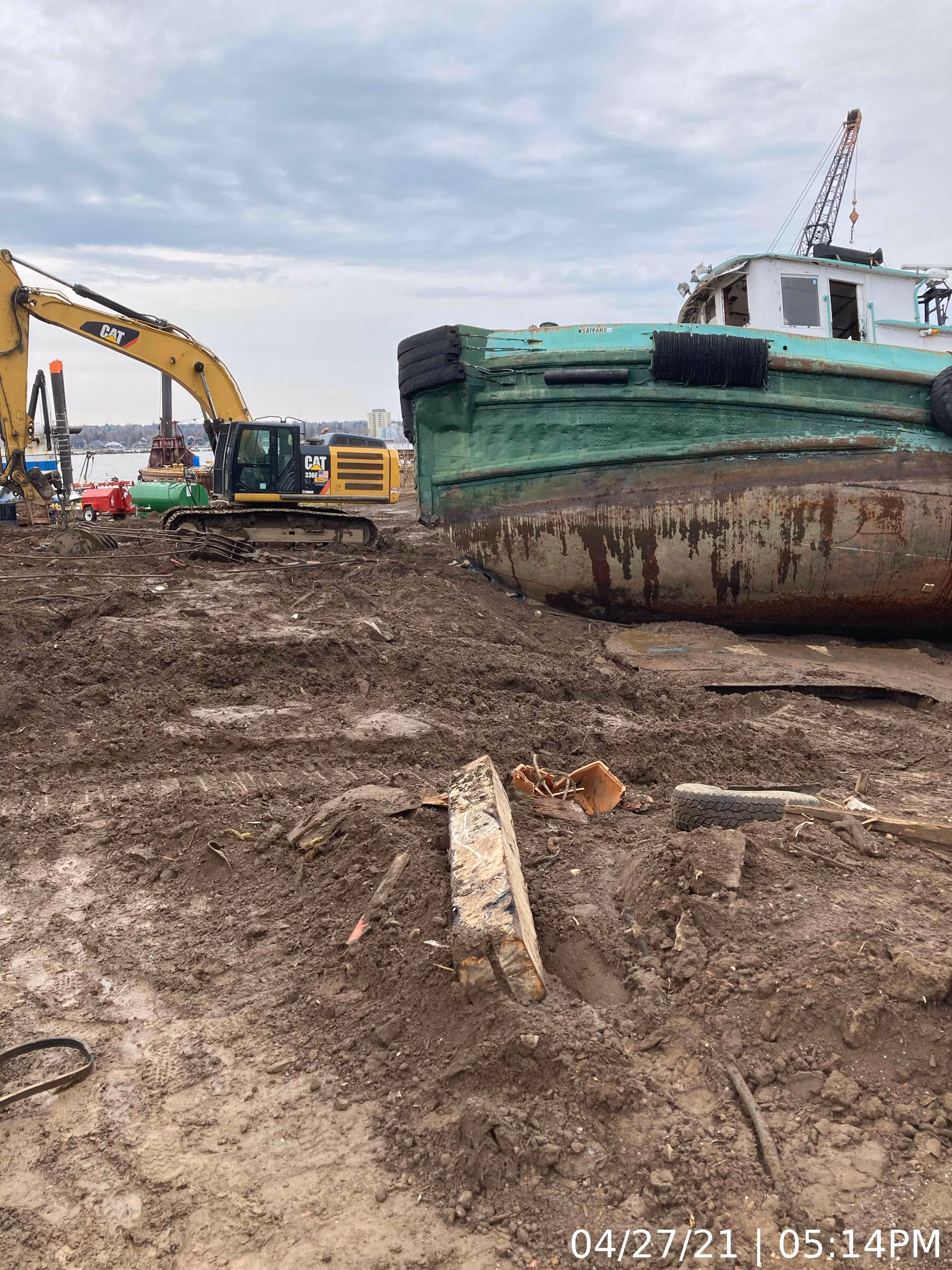 A boat sits on the ground adjacent to a crane, highlighting a scene of maritime work or equipment staging.