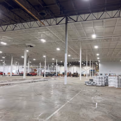 A spacious warehouse interior filled with bright lights illuminating the open area.