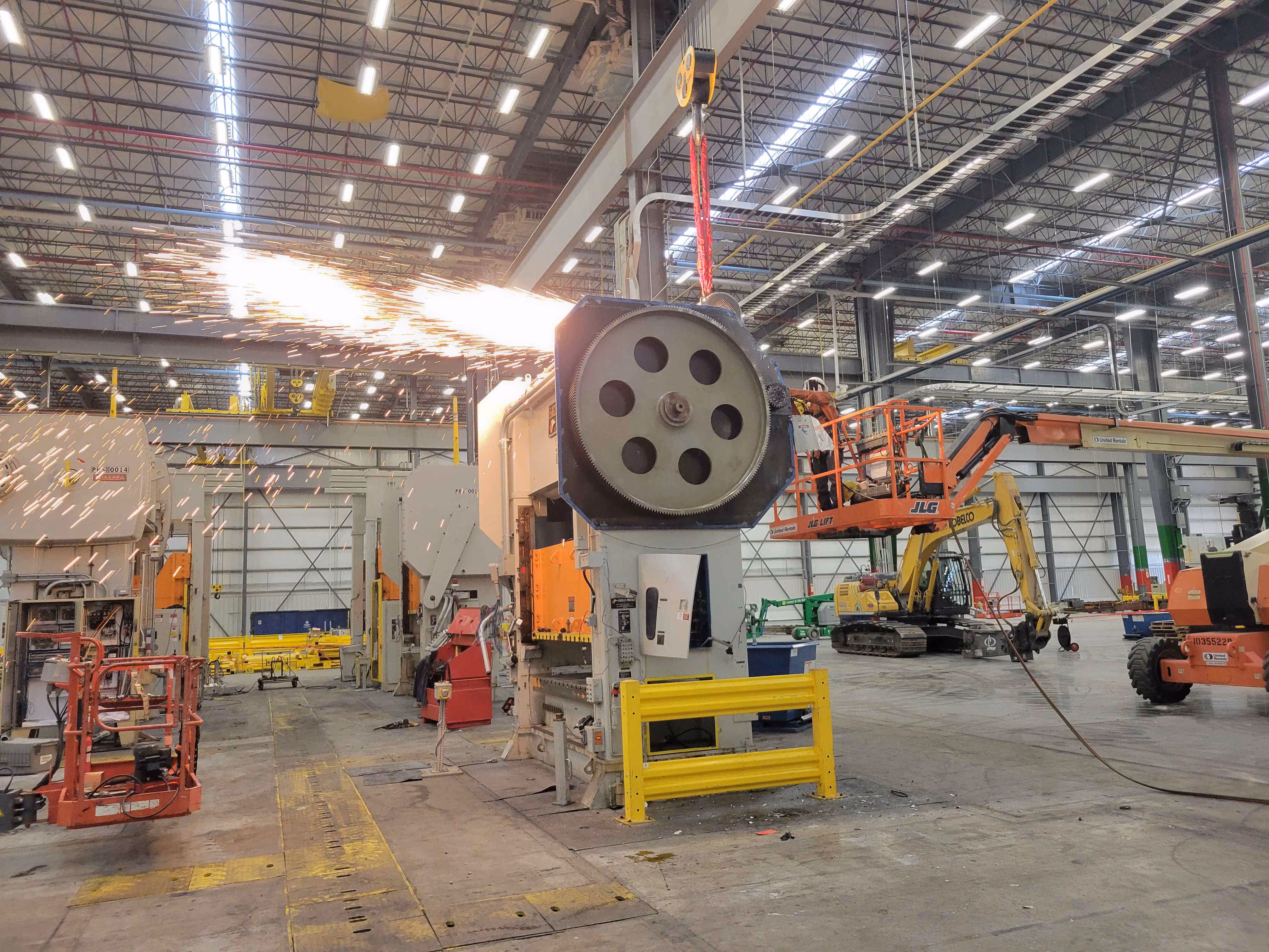 Industrial machinery dismantling in bright, active warehouse
