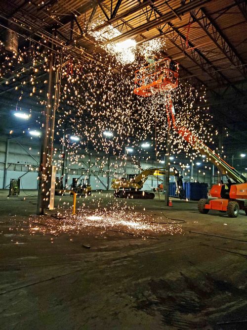 A crane is cutting a metal plate in a warehouse.