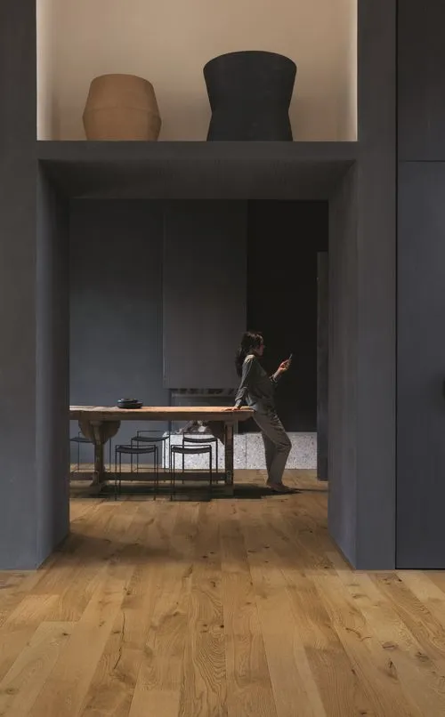 a woman standing in a room with a table and chairs