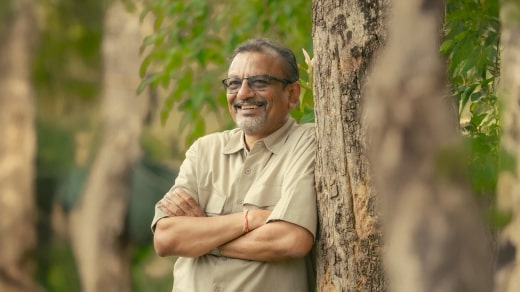 A smiling yurt owner standing in front of their fully set-up yurt, surrounded by natural landscape, with a cozy deck and minimal furnishings visible—capturing their satisfaction and the serene environment.