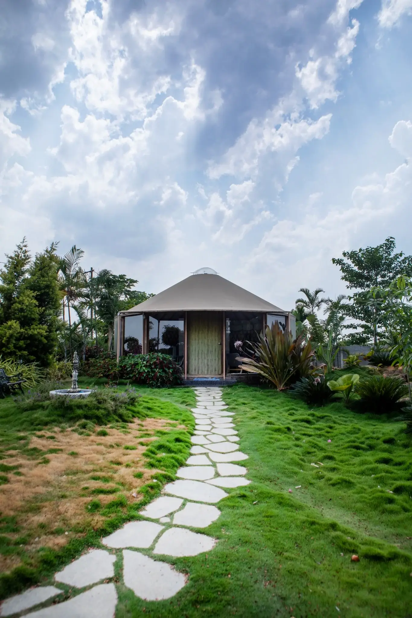 Sustainable yurt with landscaped garden and natural stone pathway under dramatic sky