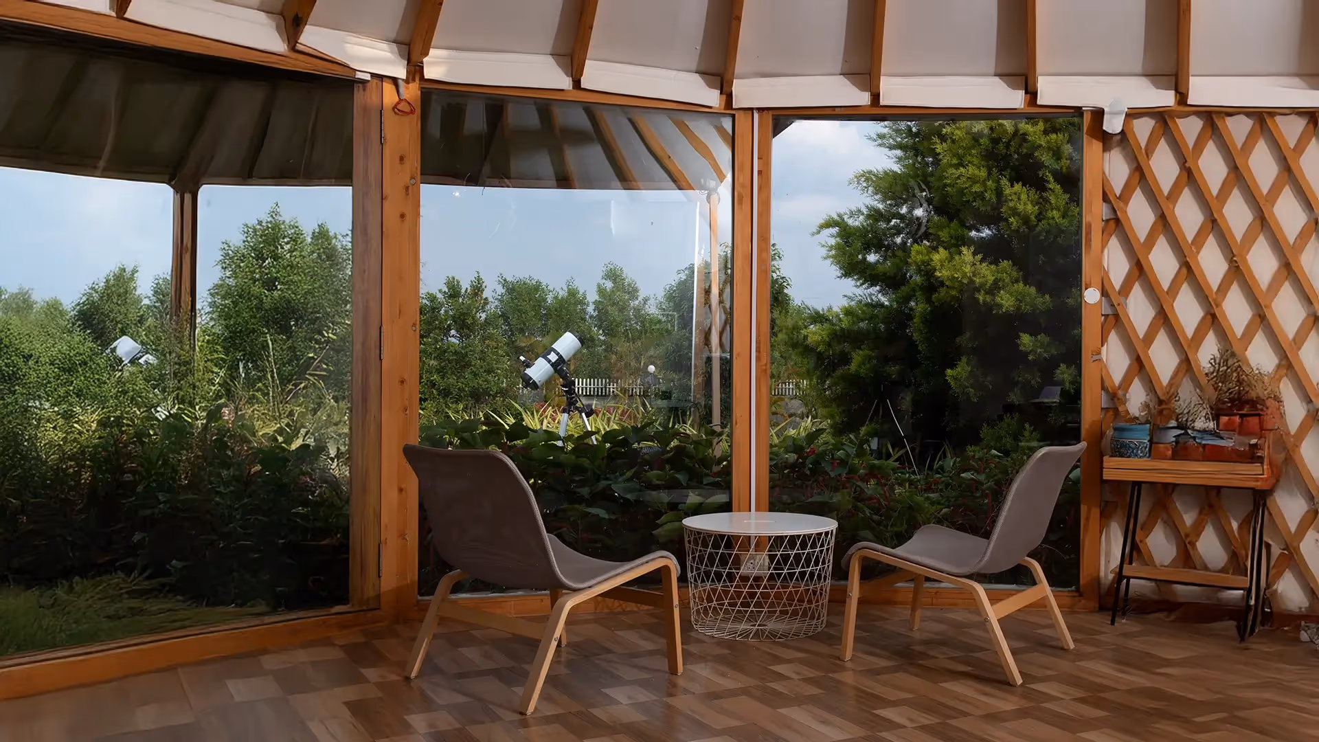 Contemporary yurts on raised platforms with rustic fencing in a forest glamping site